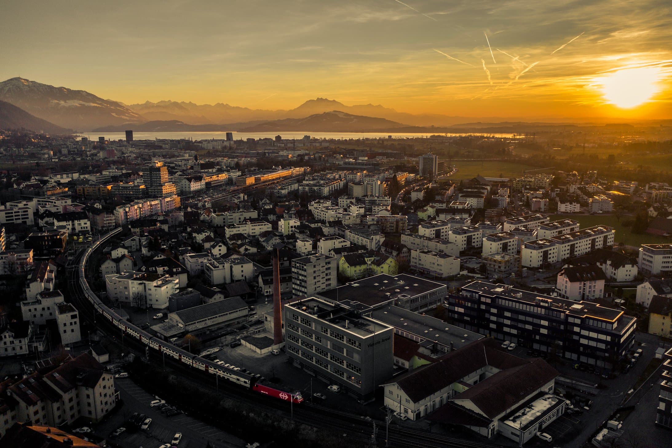 Stadtansicht von Zug in der Schweiz bei Sonnenuntergang mit Bahnlinie – regionale Verankerung von bucherimparting